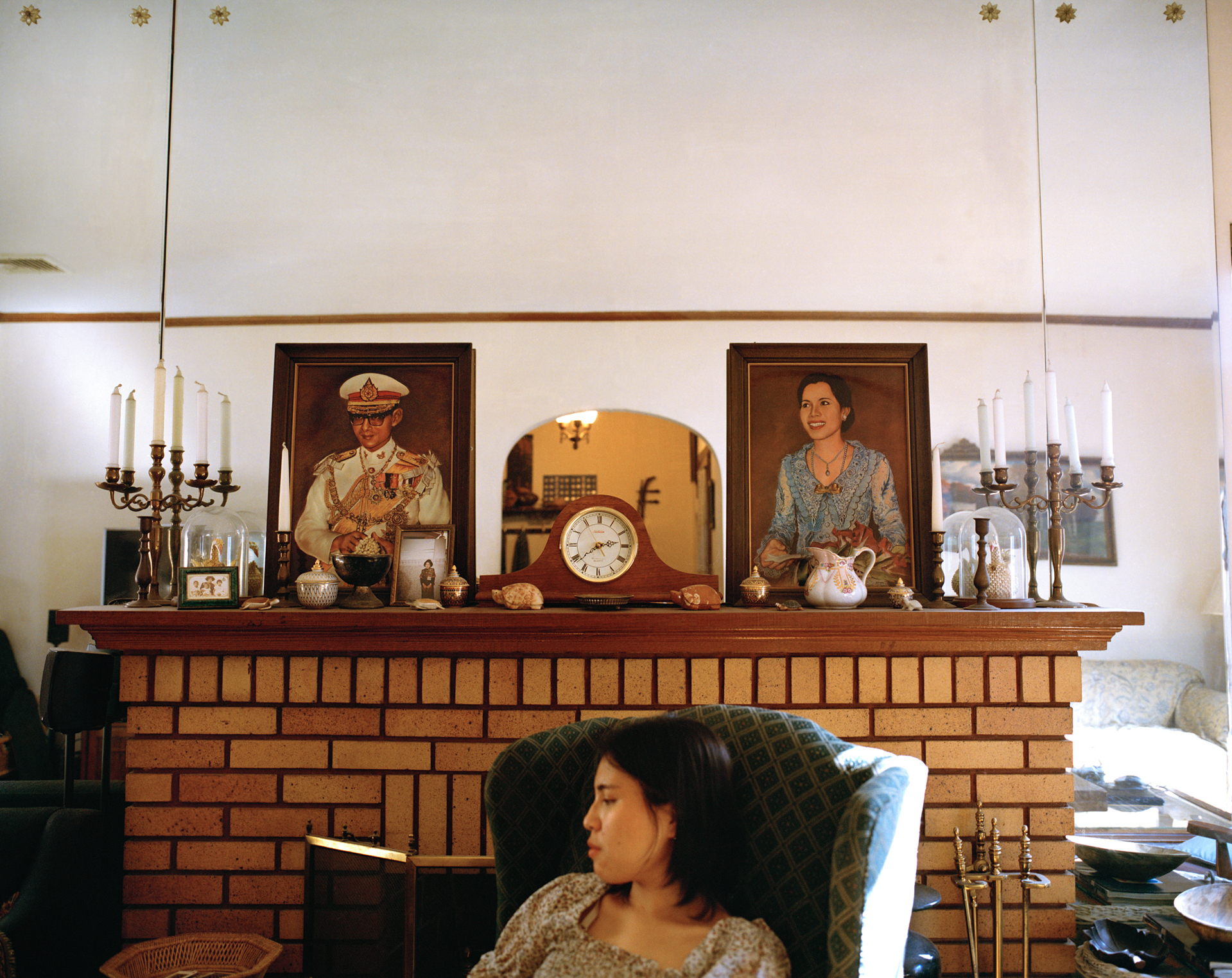 person sitting in front of a mantel with family photos on it